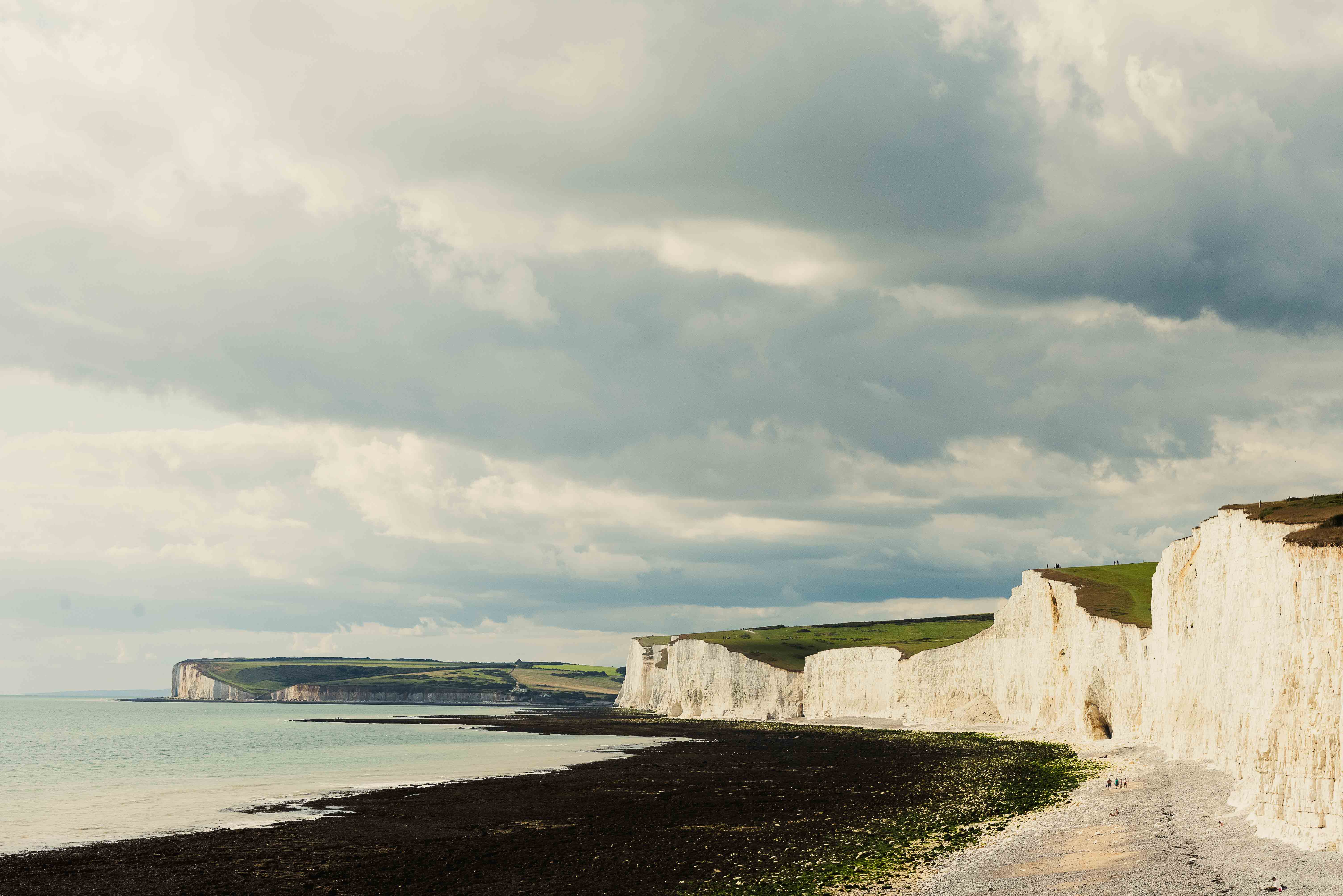 Scenic view of dramatic white cliffs along a coastline under a cloudy sky.