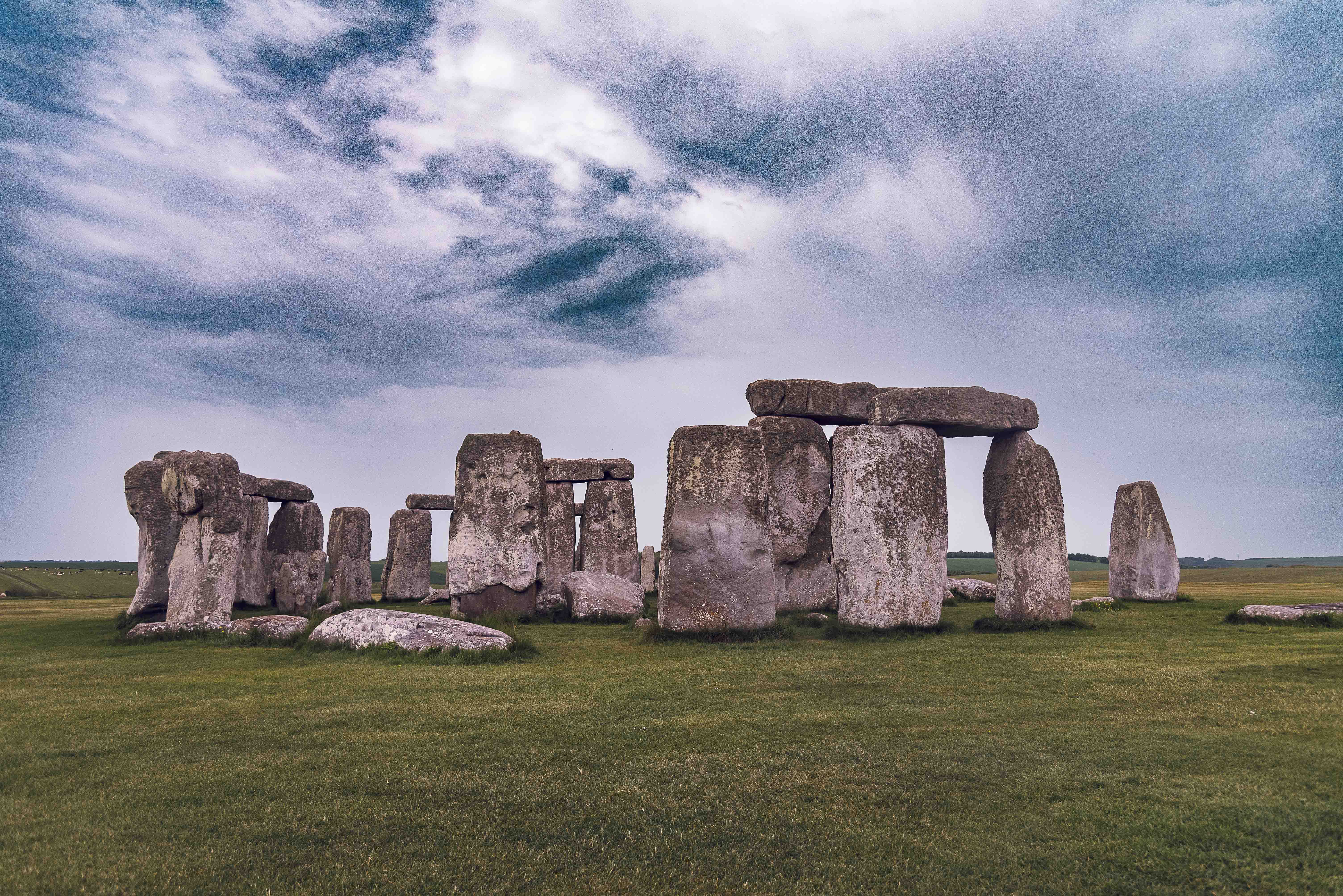 Stonehenge with an overcast sky, featuring large stone upright structures and horizontal lintels, set in a grassy landscape.